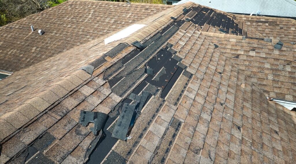 Damaged house roof with missing shingles